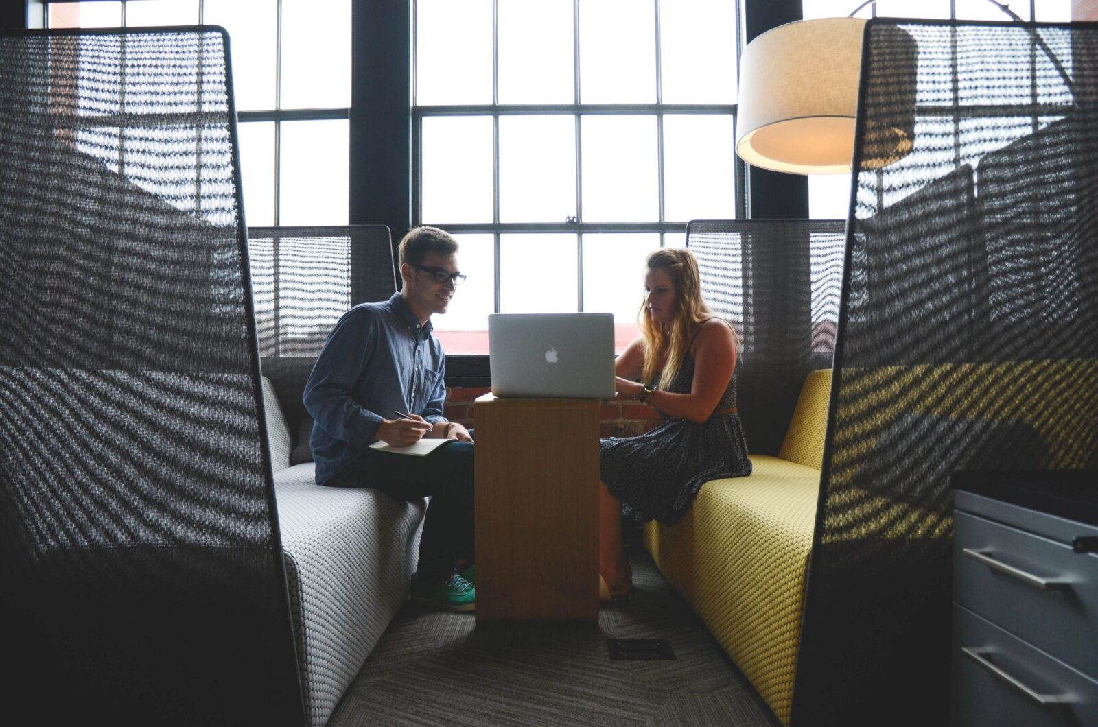 Two people collaborating in modern office booth.
