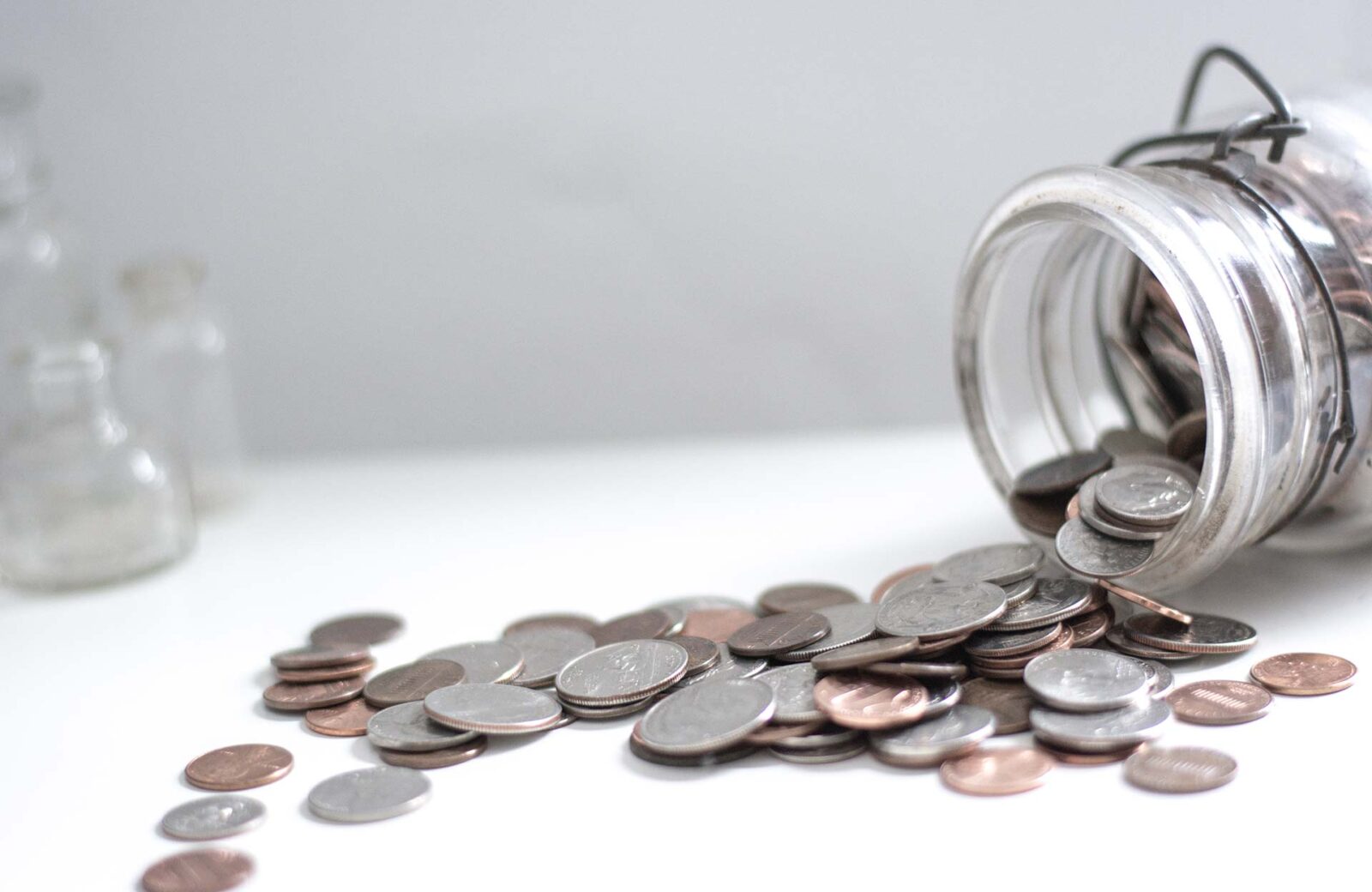 Coins spilling from glass jar.